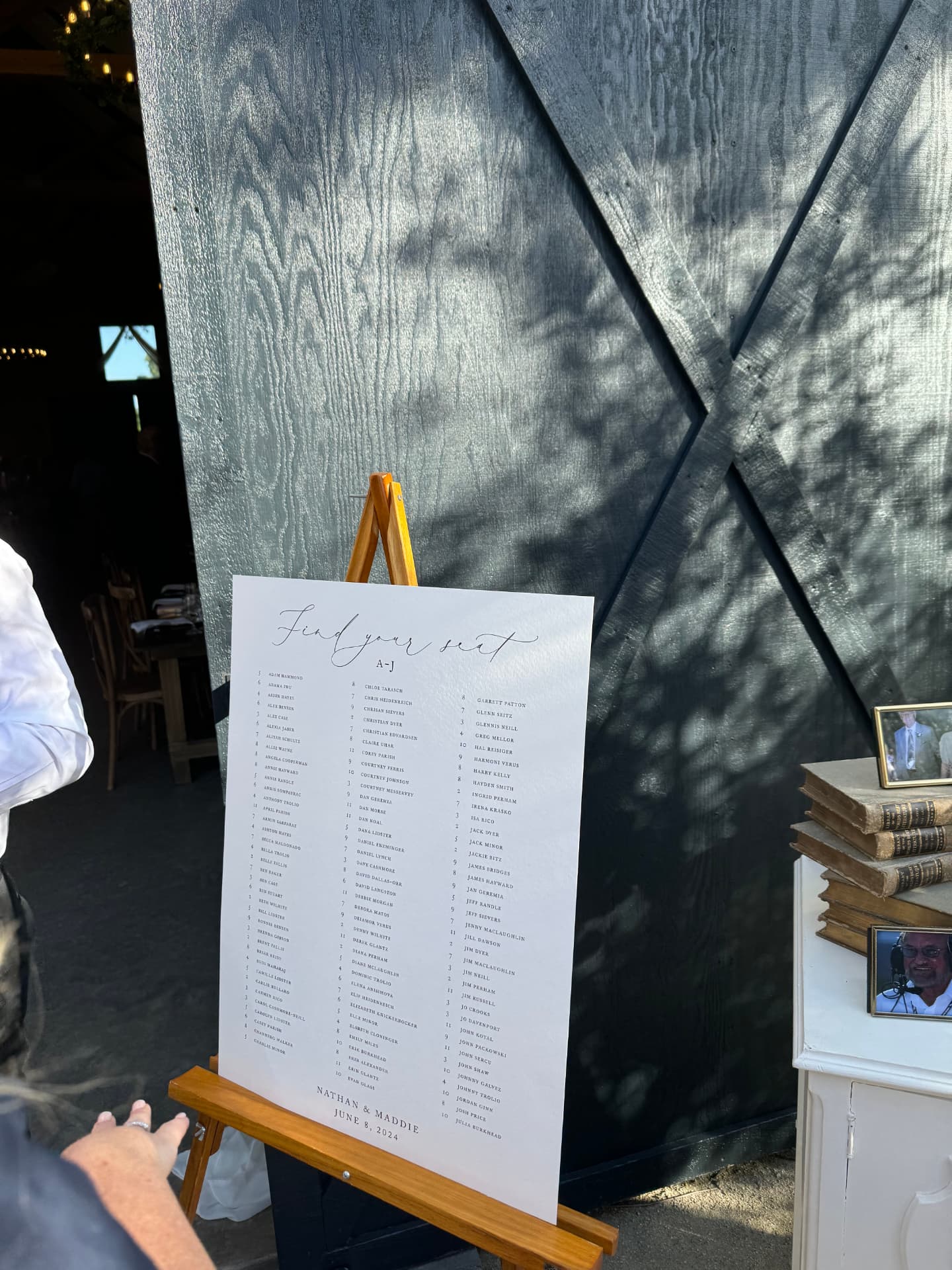 Calligraphed 'Find your seat' seating chart on an easel beside the barn doors