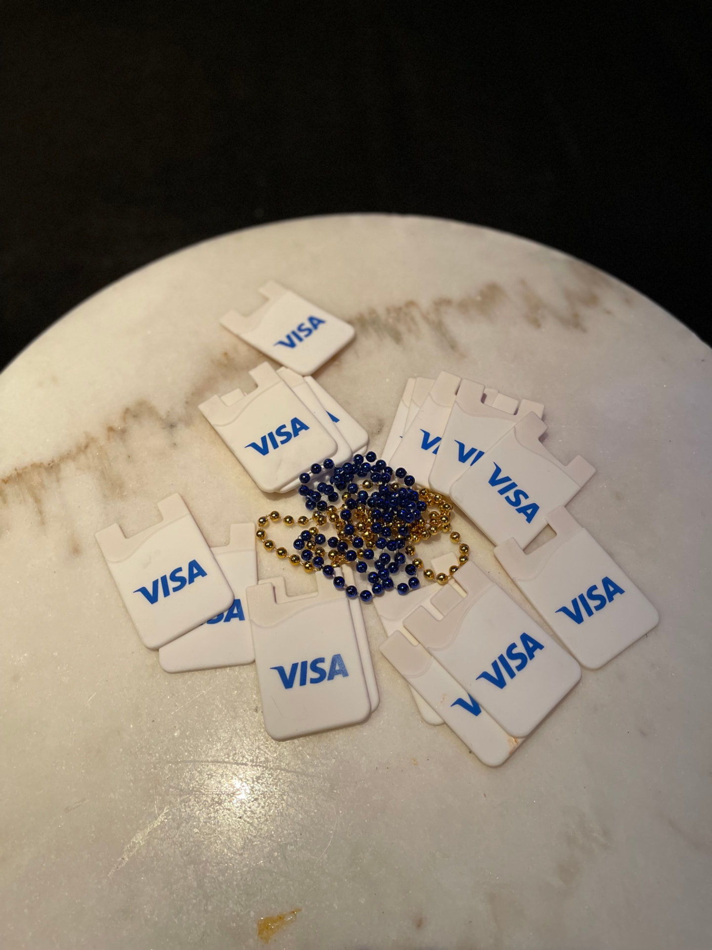 Visa-branded phone card wallets and blue and gold bead necklaces on a marble table
