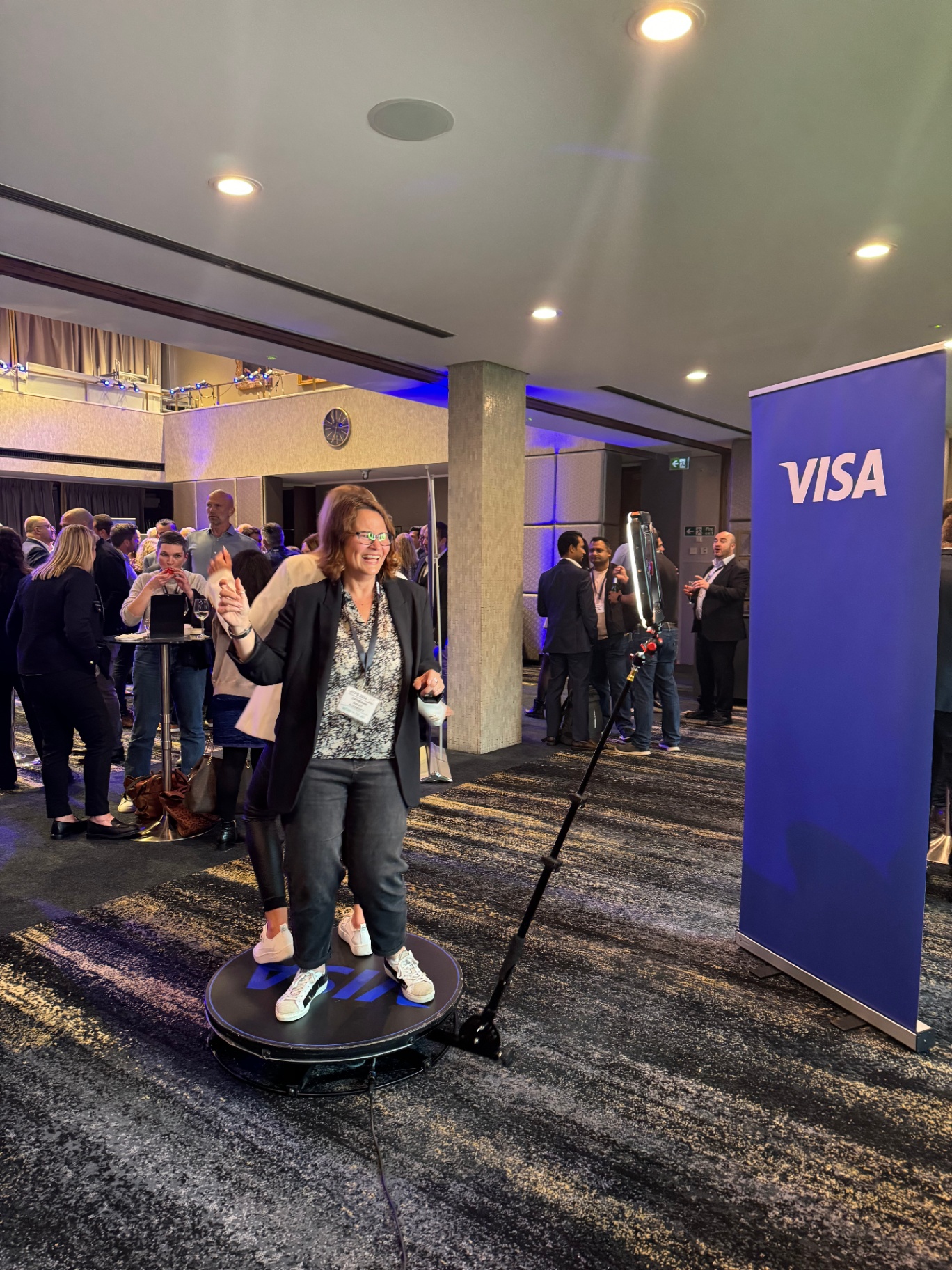 Guest on the 360 photo booth platform beside a Visa banner