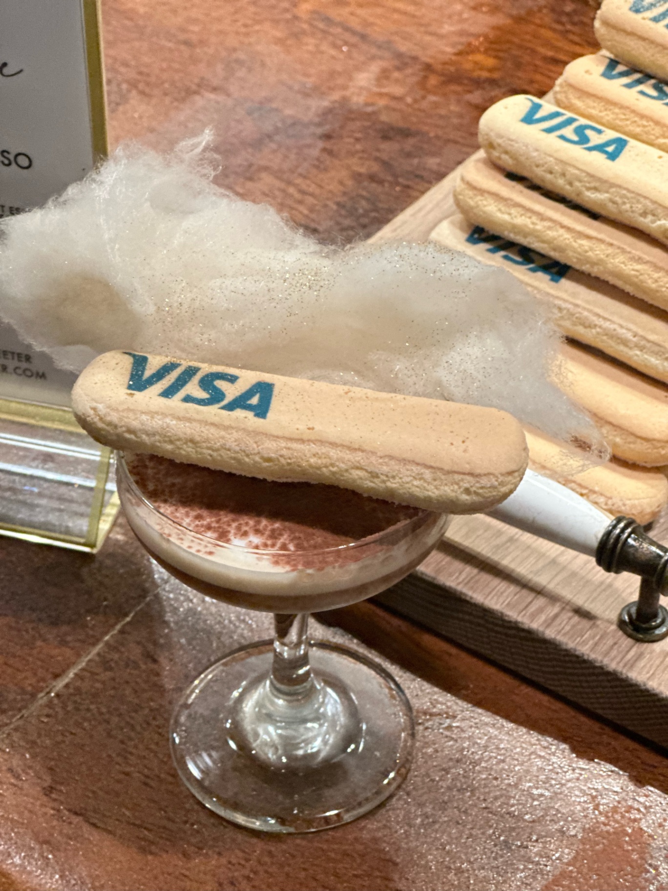Visa-branded ladyfinger cookie on an espresso martini with spun sugar