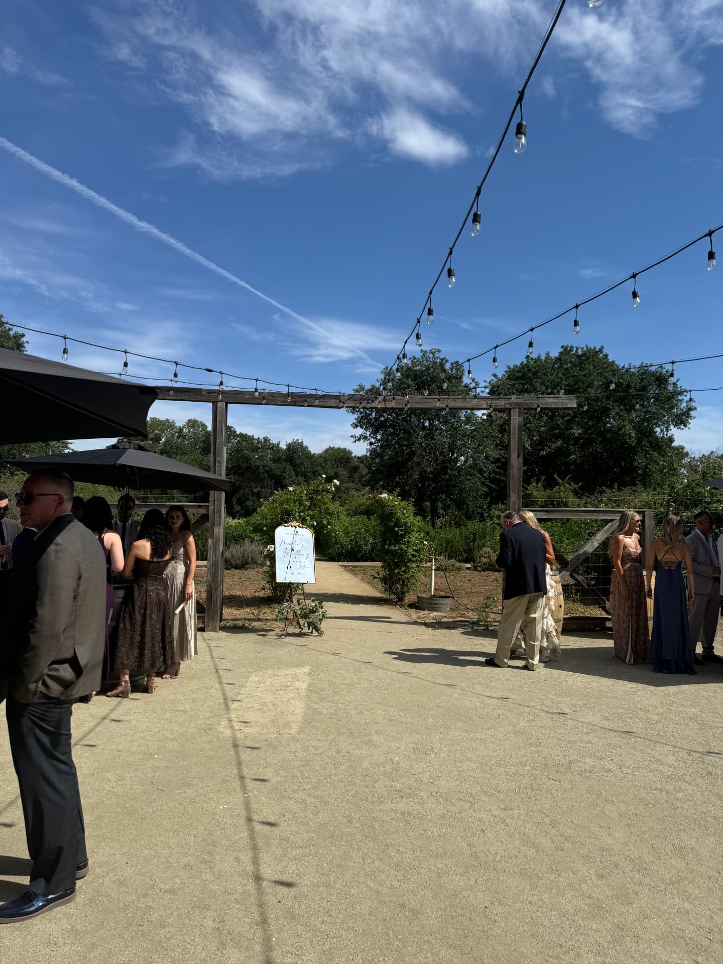 Cocktail hour under string lights in a garden courtyard with welcome signage