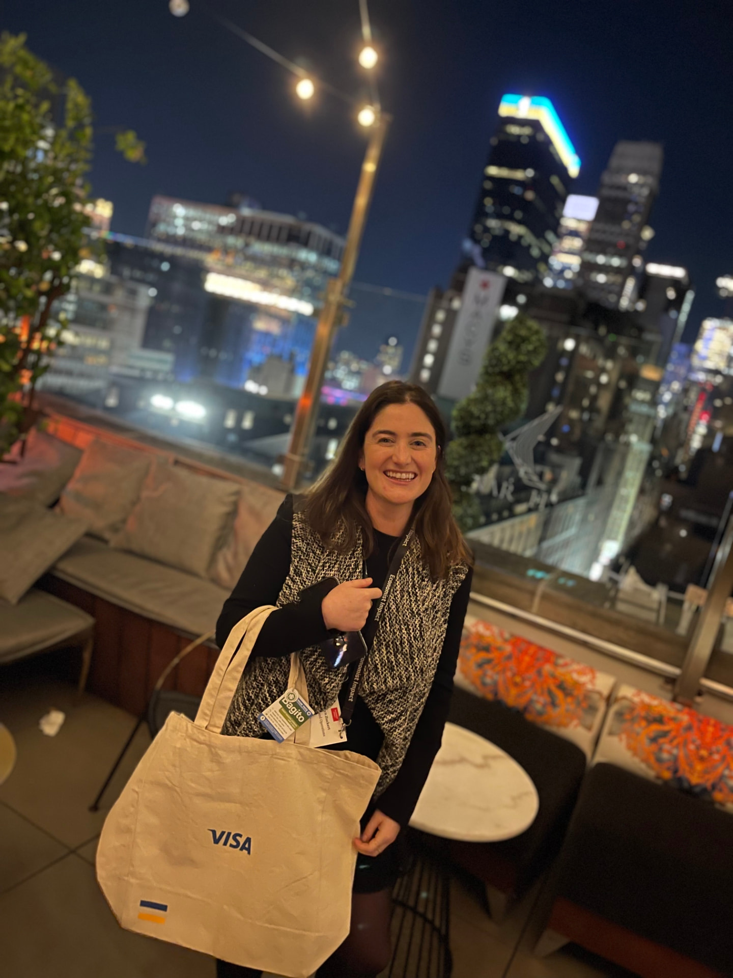 A guest smiling with her Visa tote bag at the rooftop reception