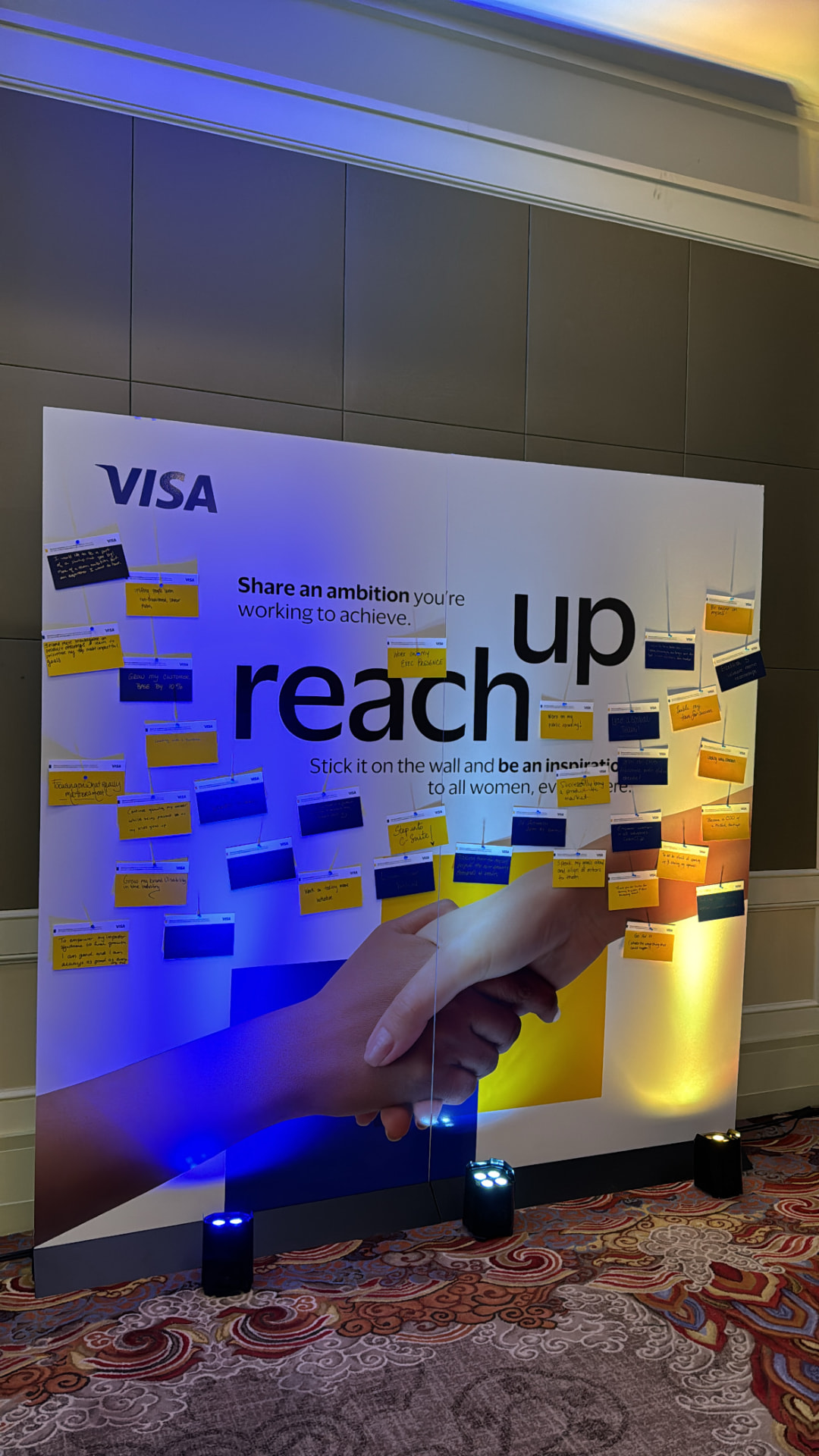 Ambition wall filled with handwritten guest notes under blue and gold lighting