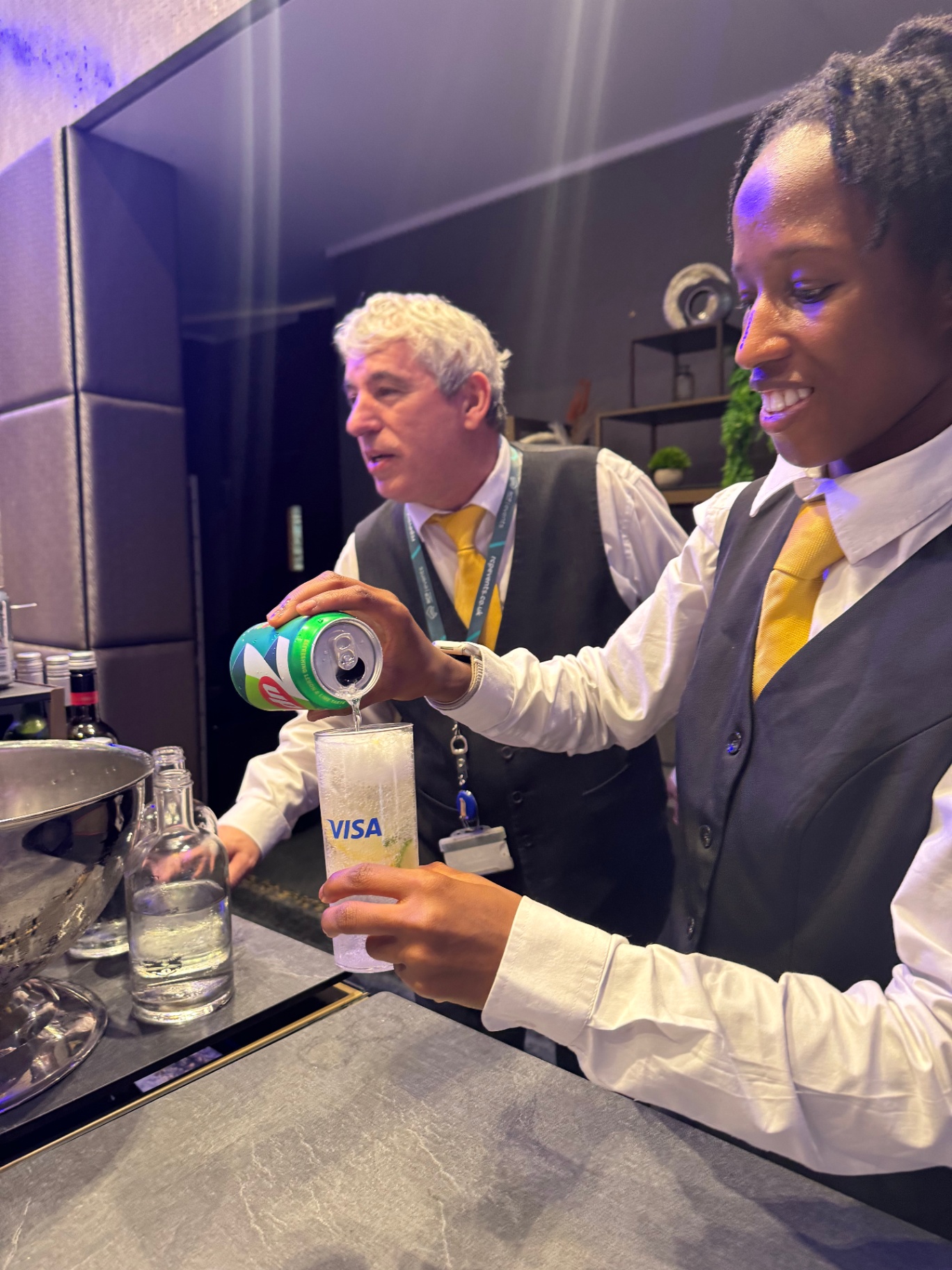 Bartender pouring a cocktail into a Visa-branded glass