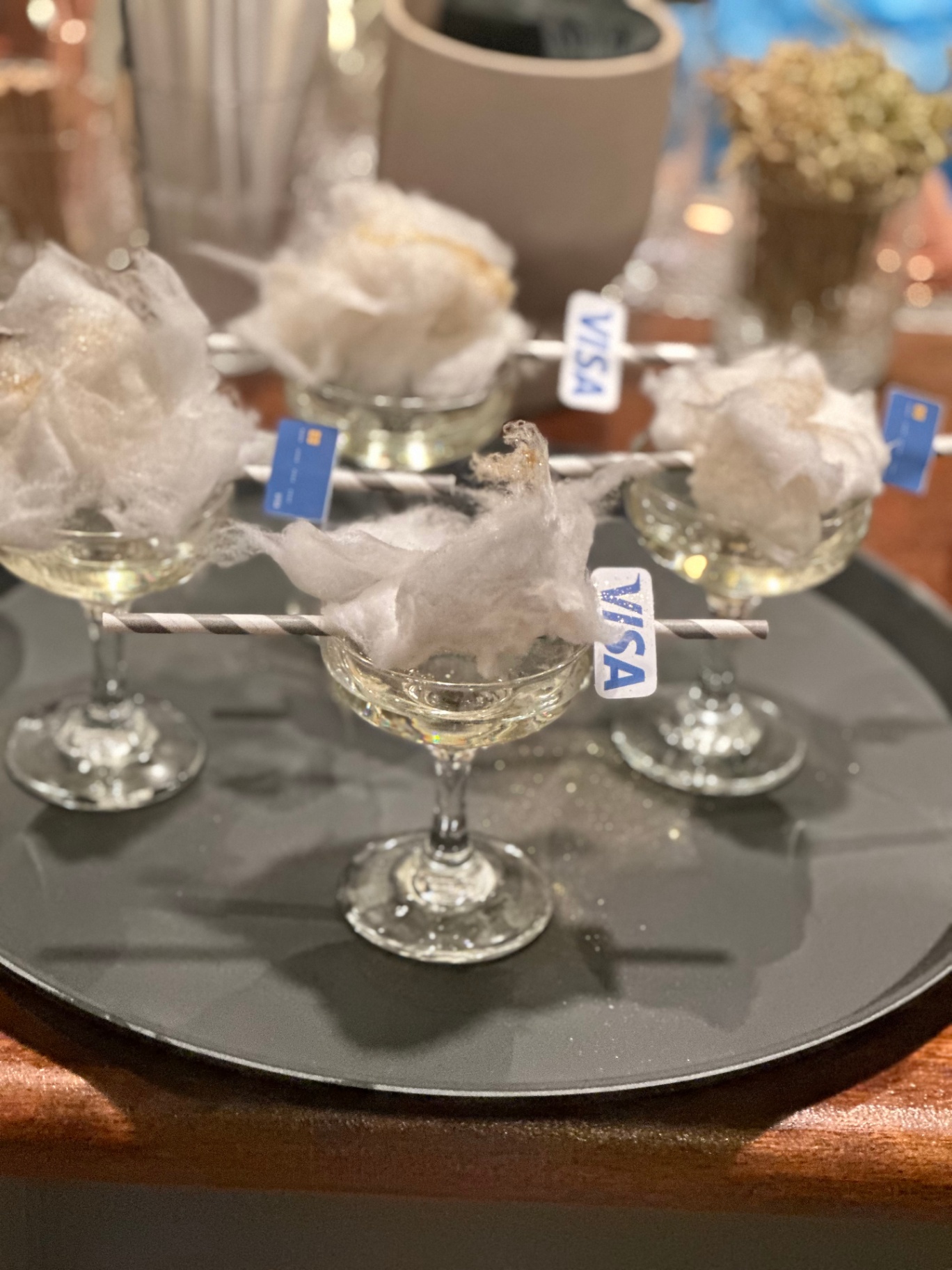 Coupe cocktails topped with cotton candy and Visa card stirrers
