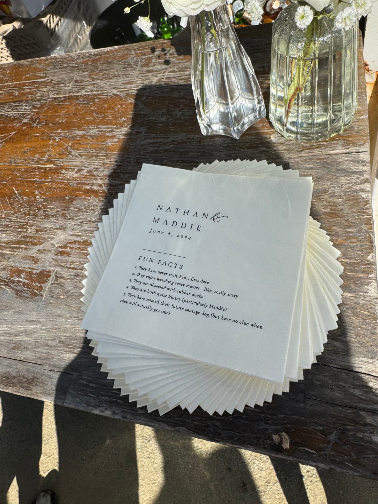 Custom 'Fun Facts' ceremony programs fanned on a rustic wooden table