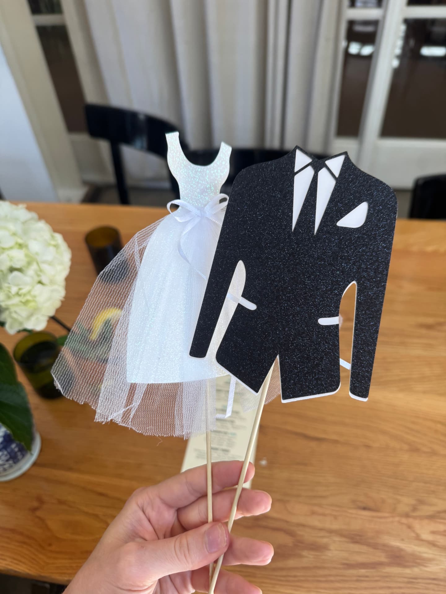 Glitter bride-and-groom paper cutouts on sticks used as bridal shower game props