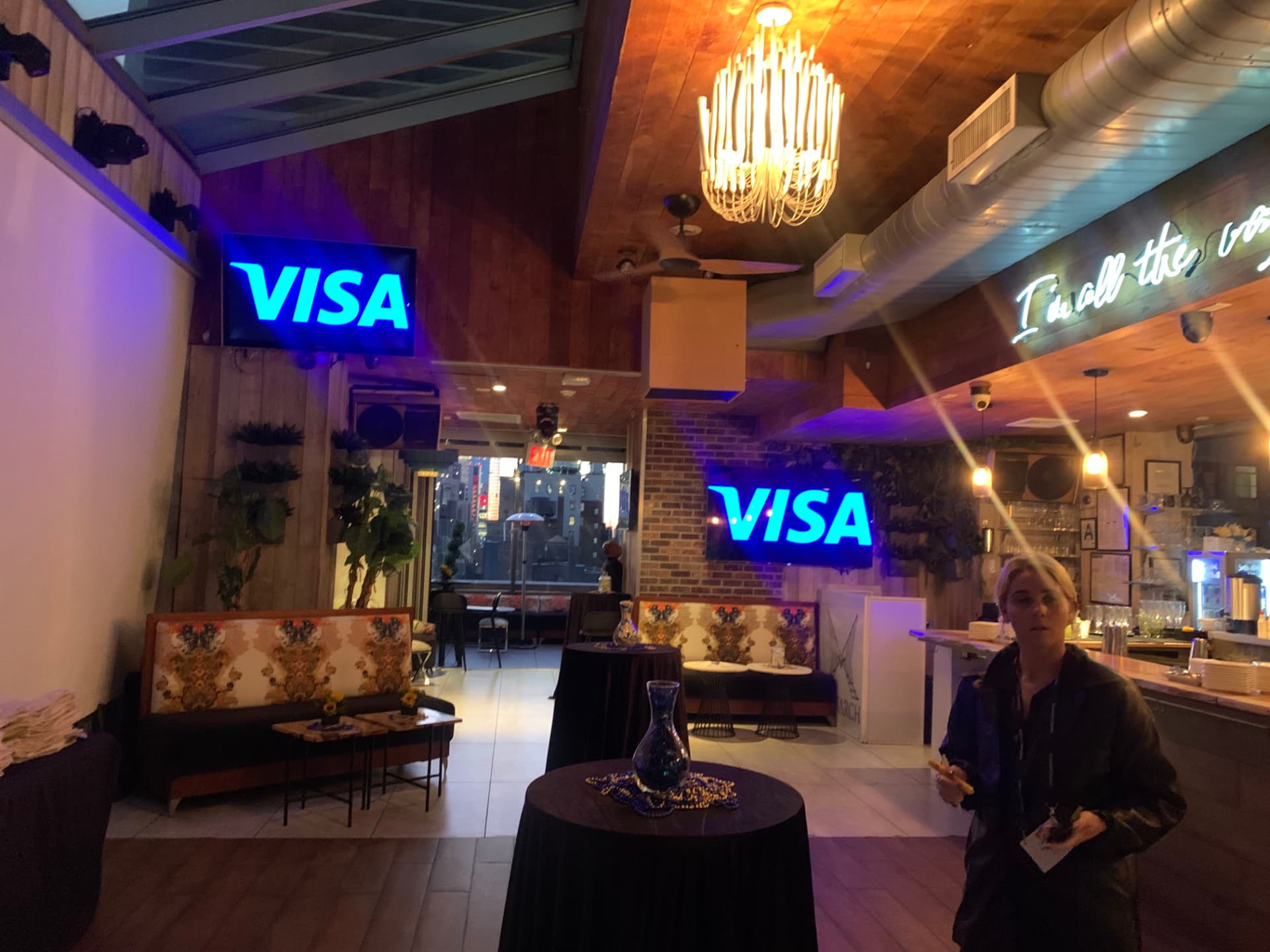 Rooftop venue with illuminated Visa screens and neon signage before the reception
