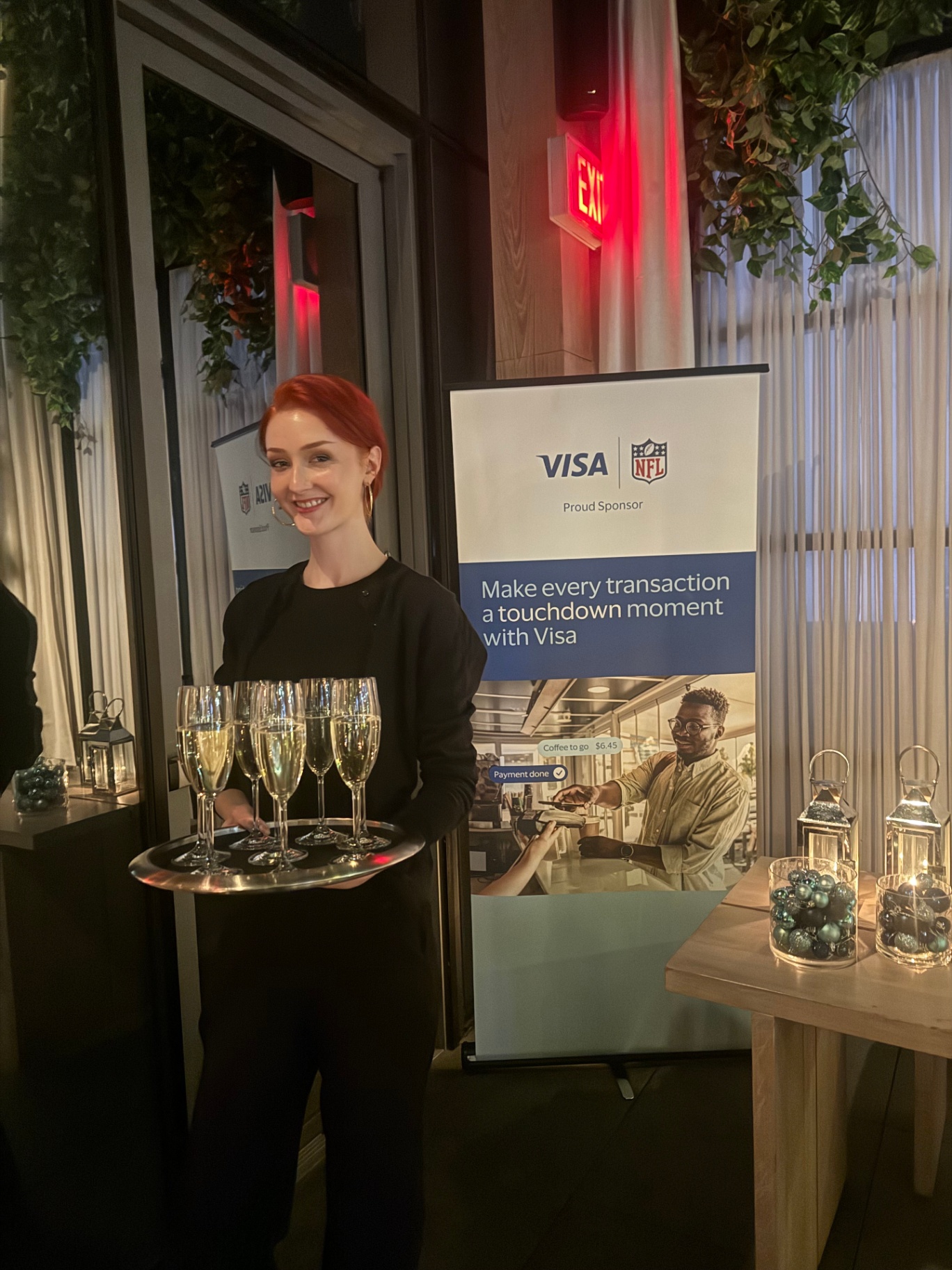 Server passing champagne beside the Visa NFL 'touchdown moment' banner