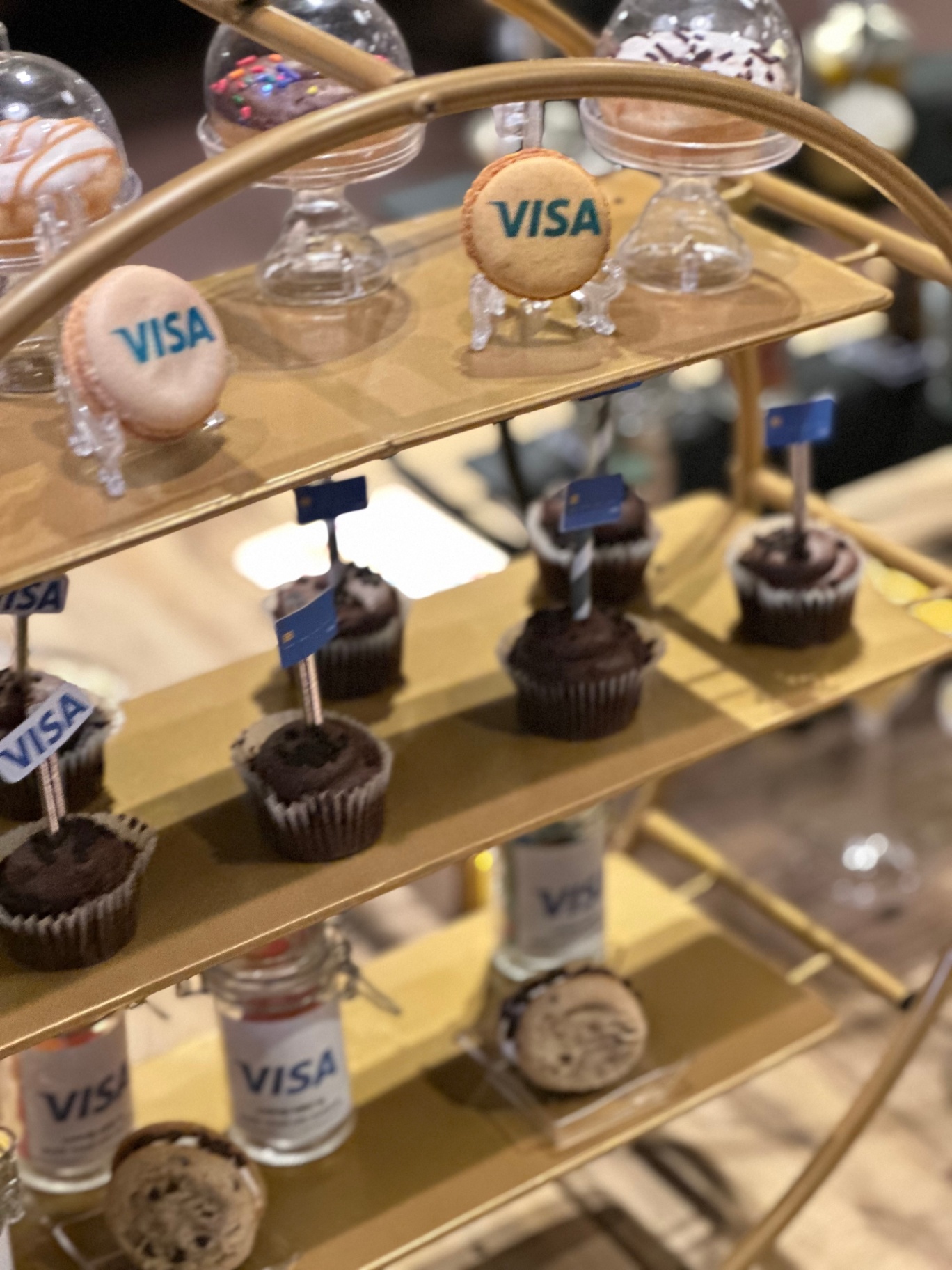 Gold dessert stand with Visa-branded macarons and chocolate cupcakes