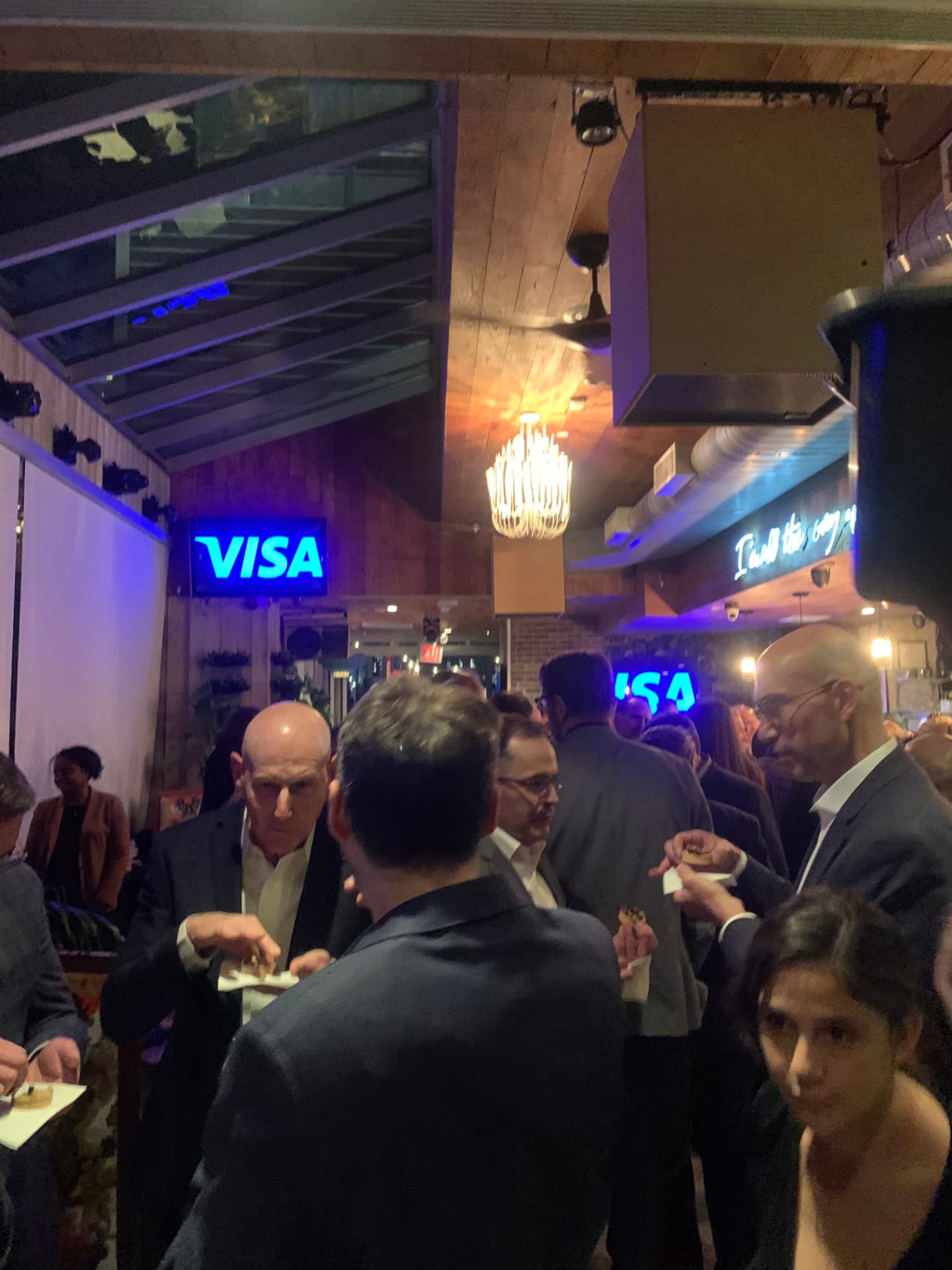 Guests mingling with bites under the Visa screens at the rooftop reception
