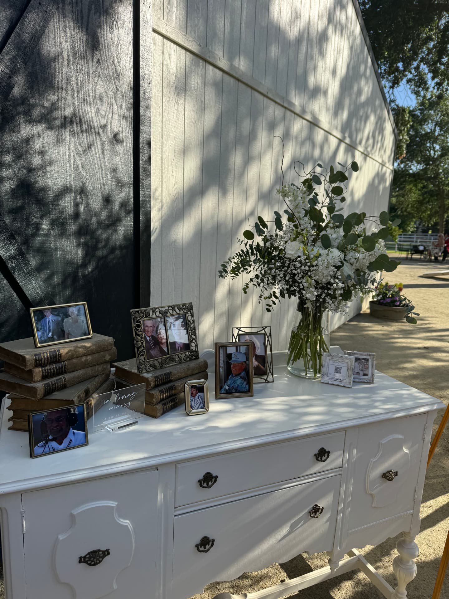 In loving memory display with framed photos, vintage books and white florals