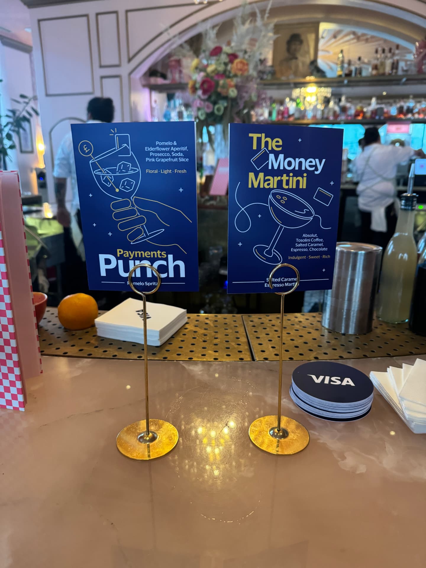 'Payments Punch' and 'The Money Martini' signature cocktail signs on the bar