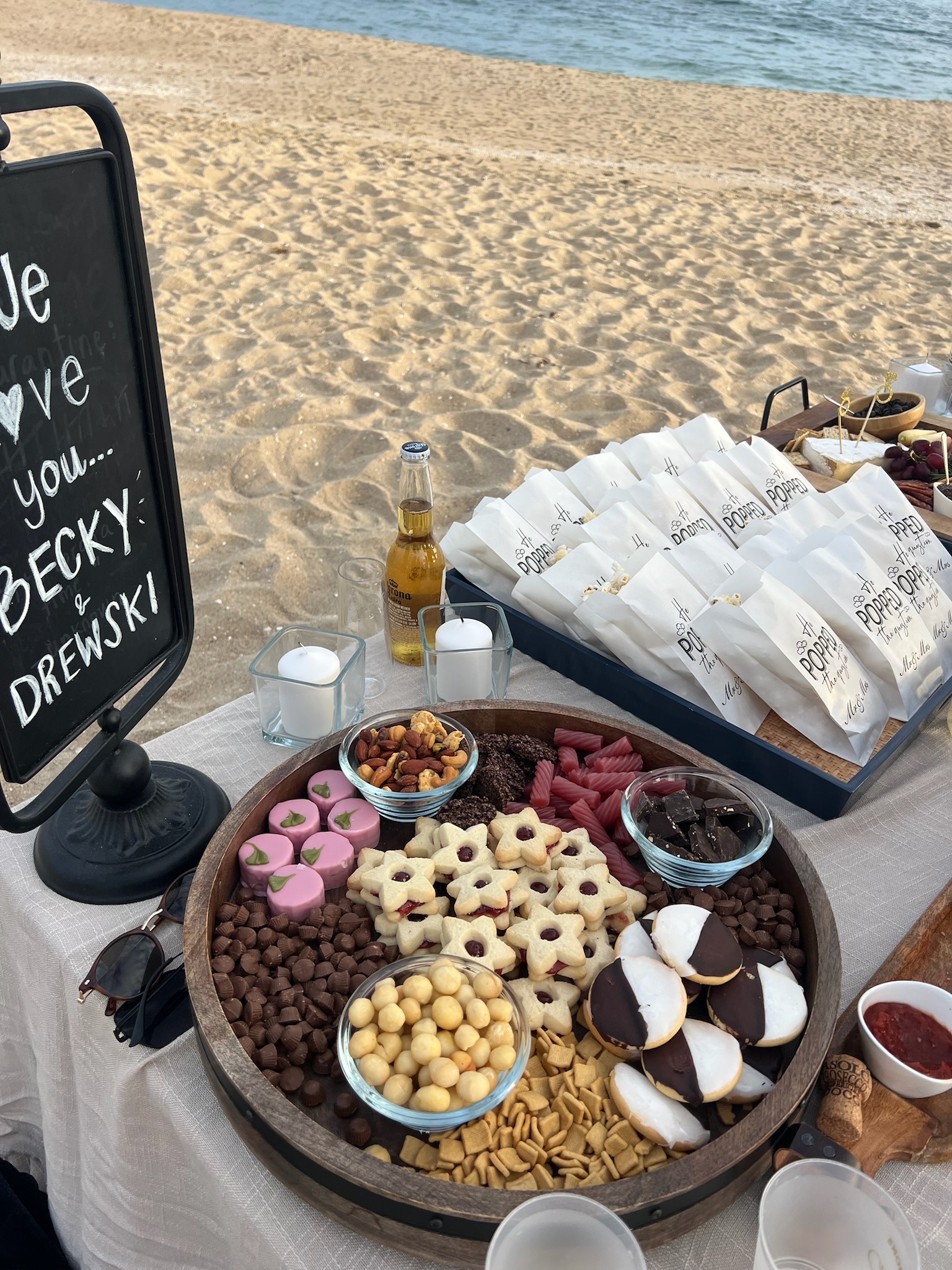 Beach engagement party - close-up of elaborate charcuterie board with chocolates and 'He POPPED the question' favor bags