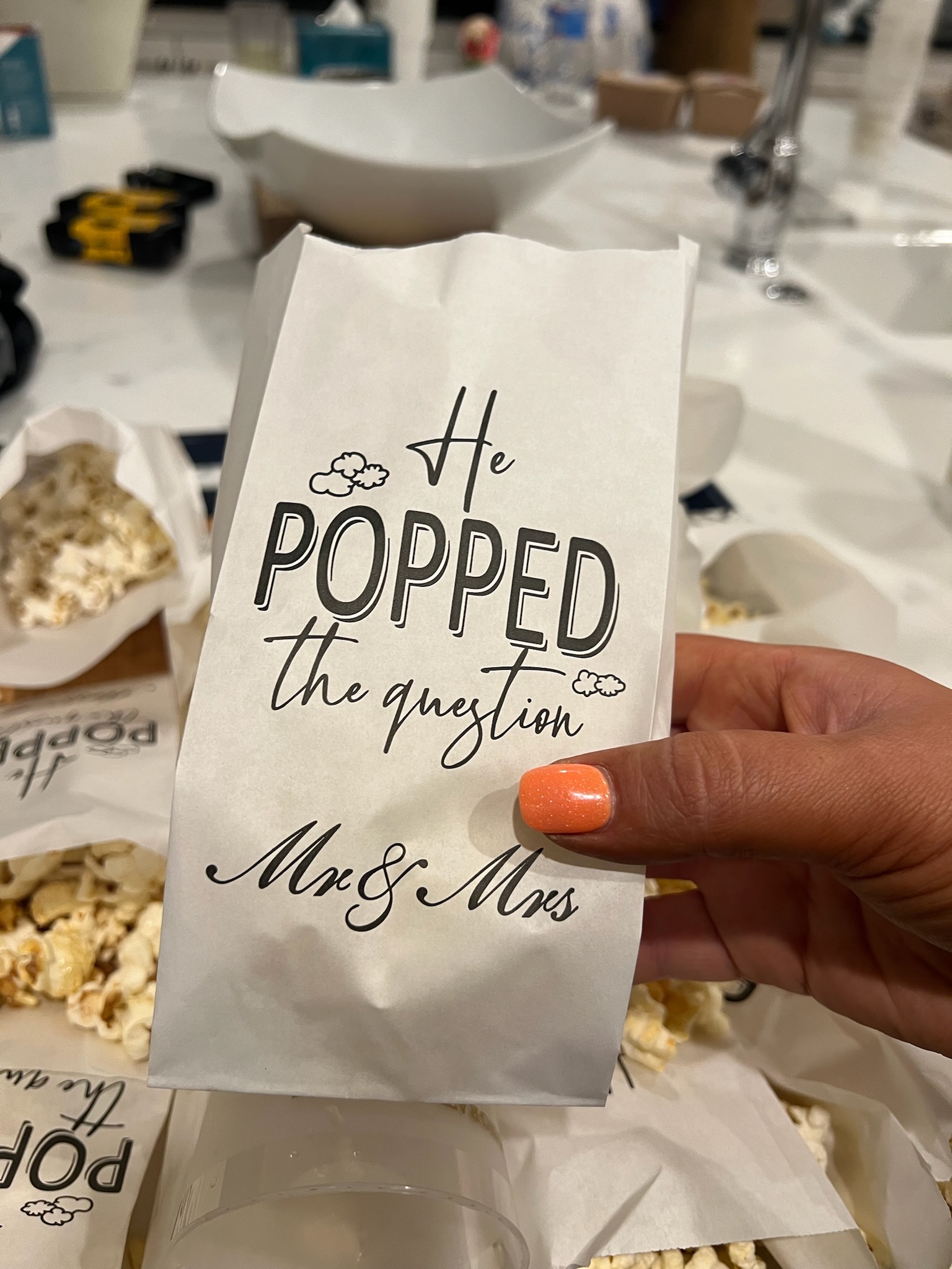 Beach engagement party - hand holding 'He POPPED the question Mr & Mrs' favor bag with popcorn treats