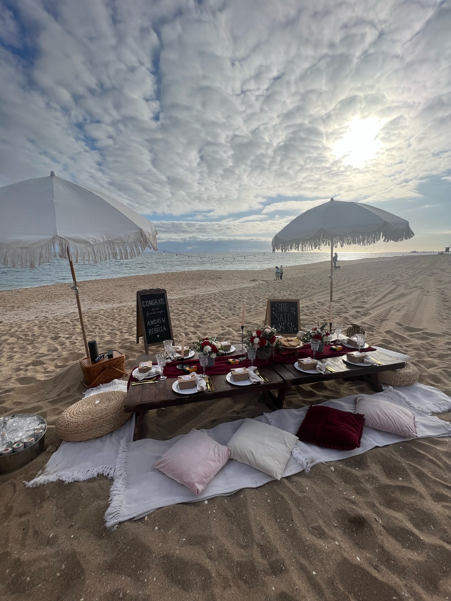Beach engagement party - dramatic sky setup with low table, burgundy runner, and floor cushions