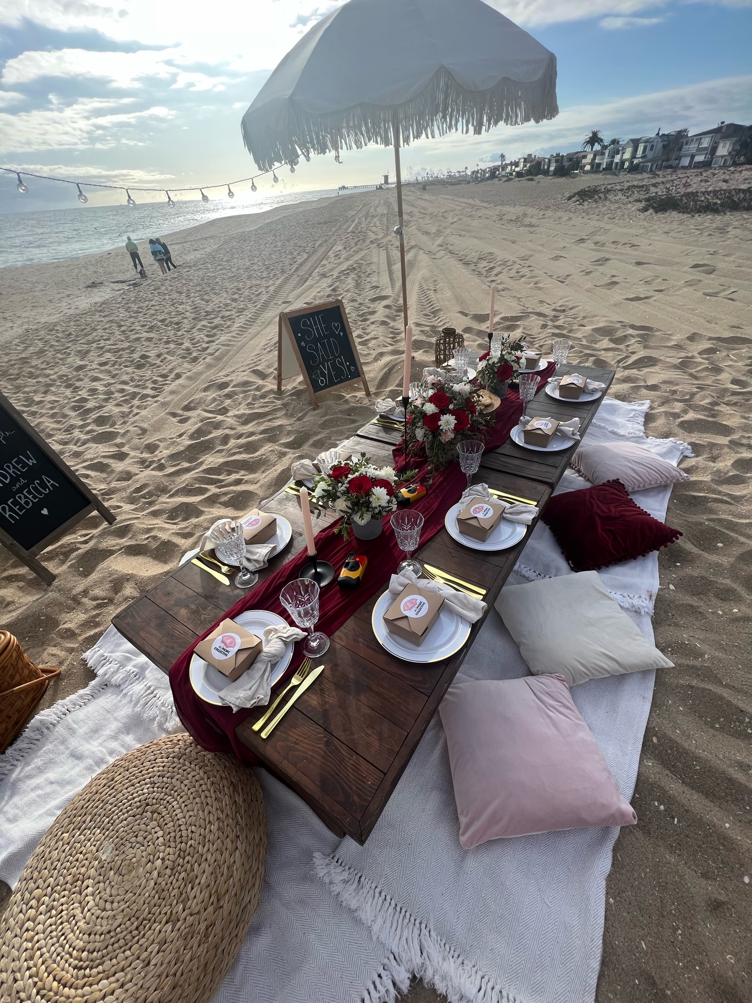 Beach engagement party - beach picnic setup with cushions and 'SHE SAID YES!' chalkboard sign