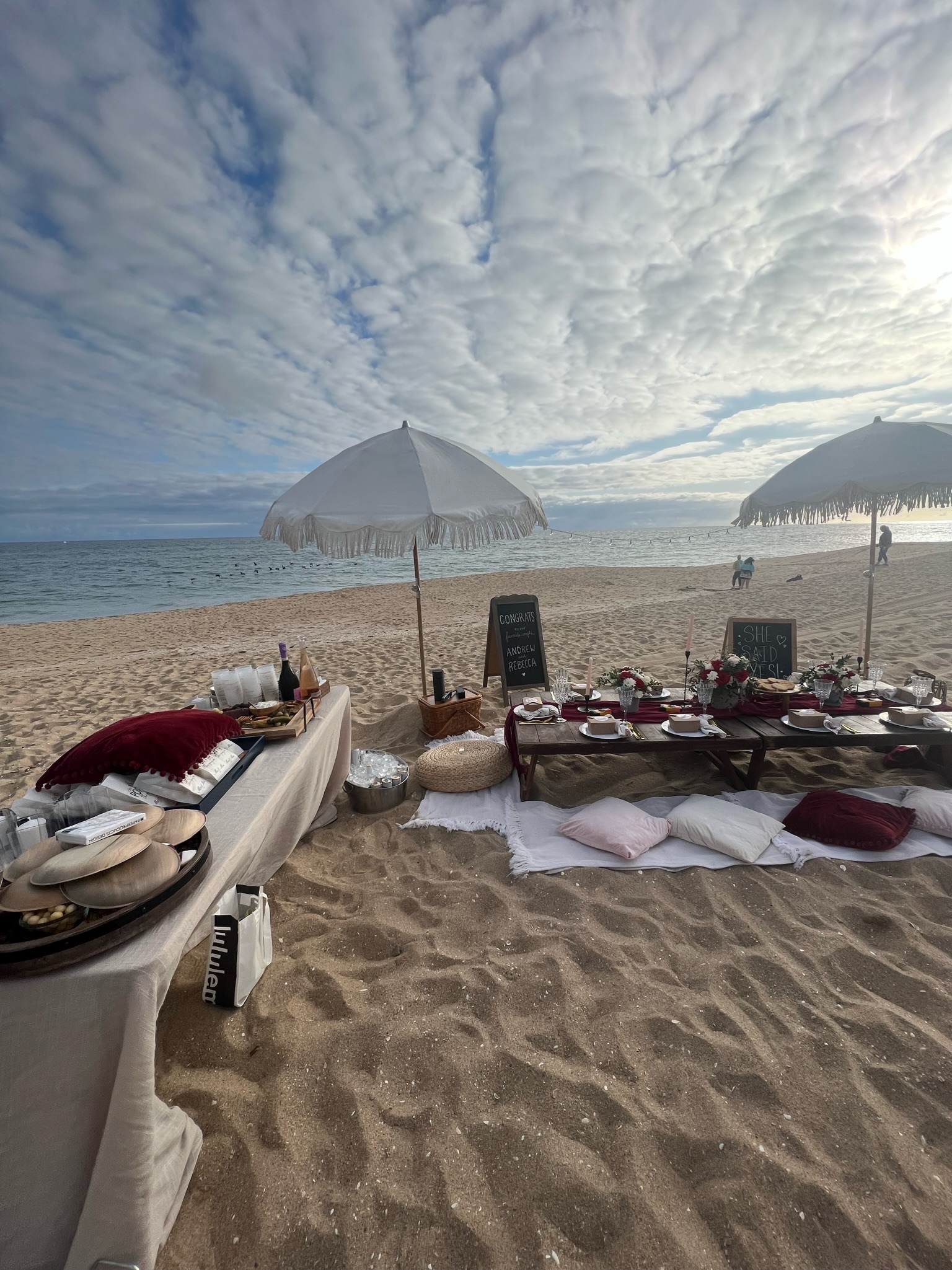 Beach engagement party - wide angle of complete setup showing dining and buffet tables with umbrellas