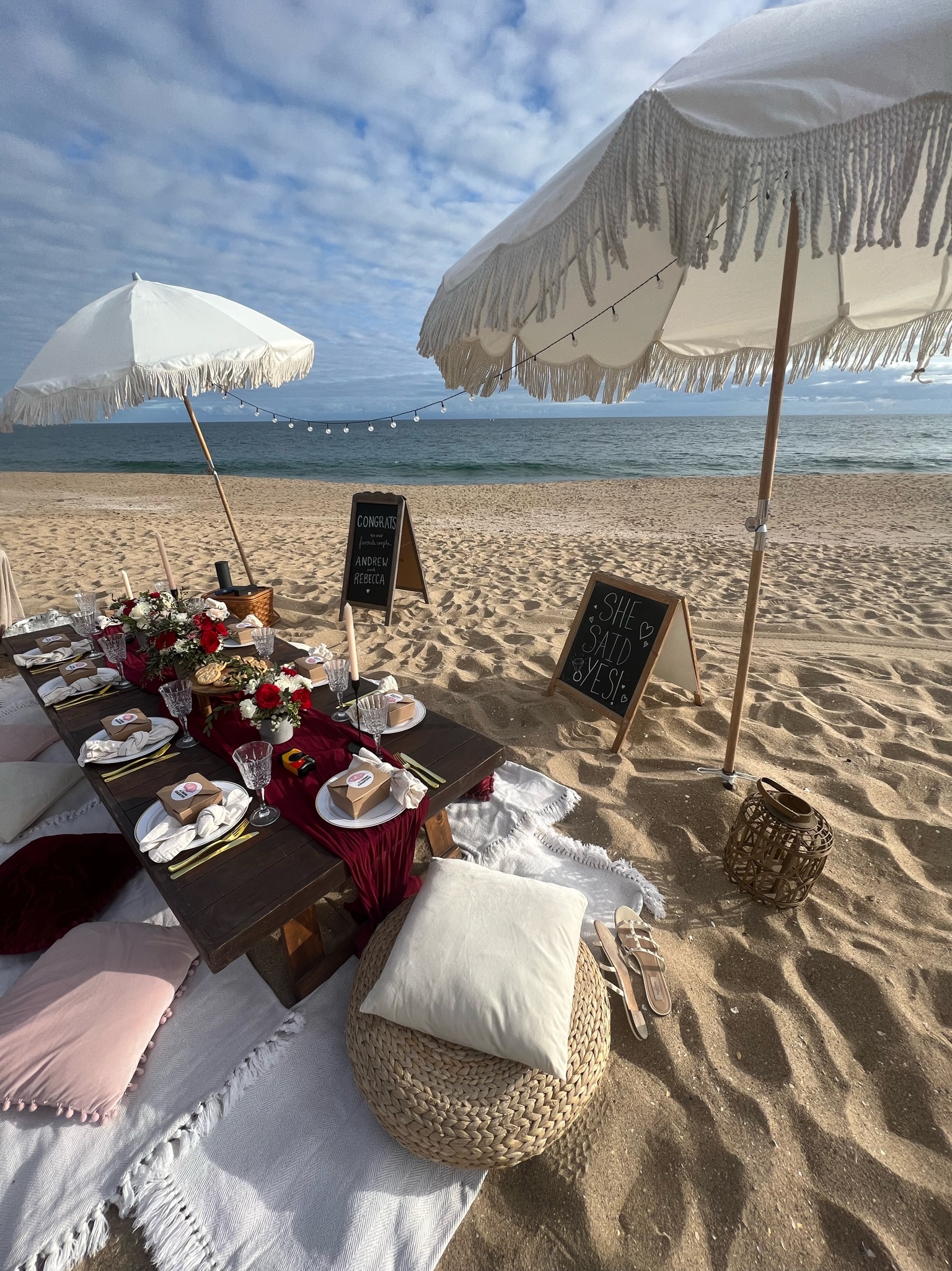 Beach engagement party - detail of low table with wicker cushions and string lights overhead