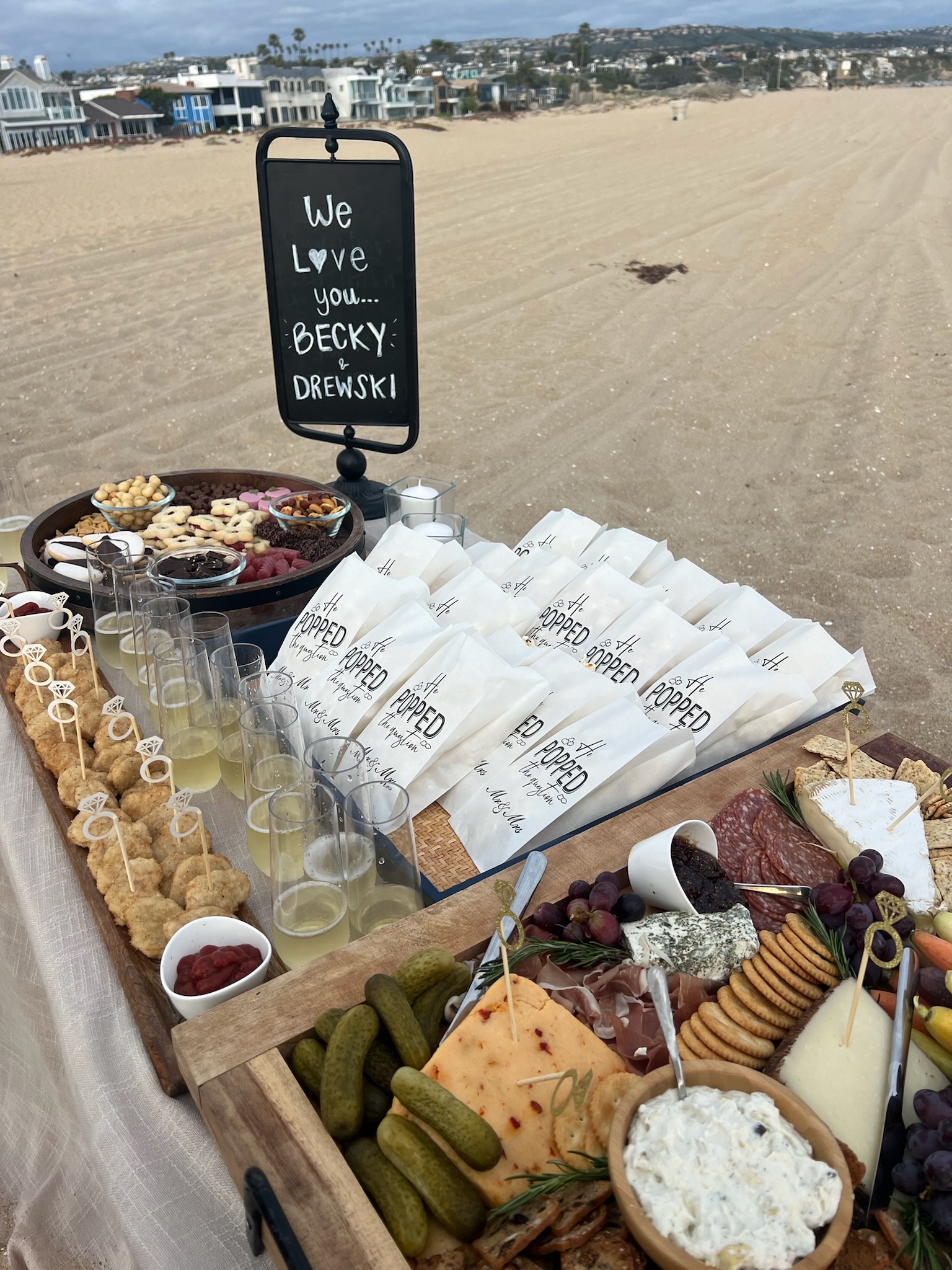 Beach engagement party - elaborate charcuterie boards with cheese, crackers, and custom favor bags on the beach