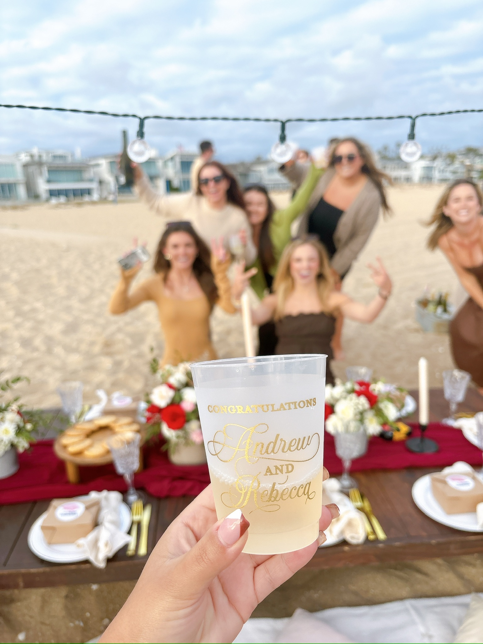 Beach engagement party - hand holding custom congratulations cup with celebration in background