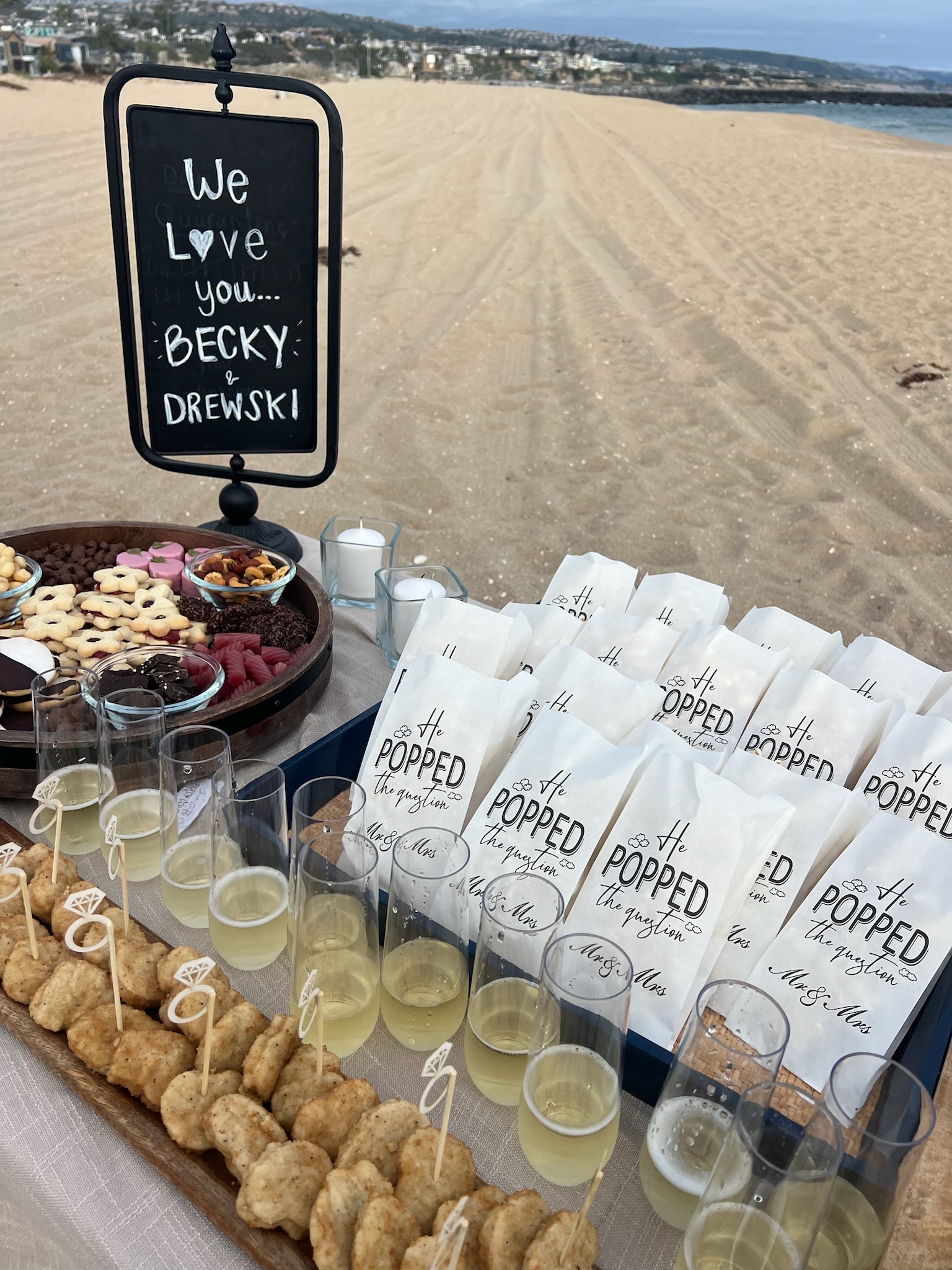 Beach engagement party - another setup shot with chalkboard sign, charcuterie spread, and favor bags