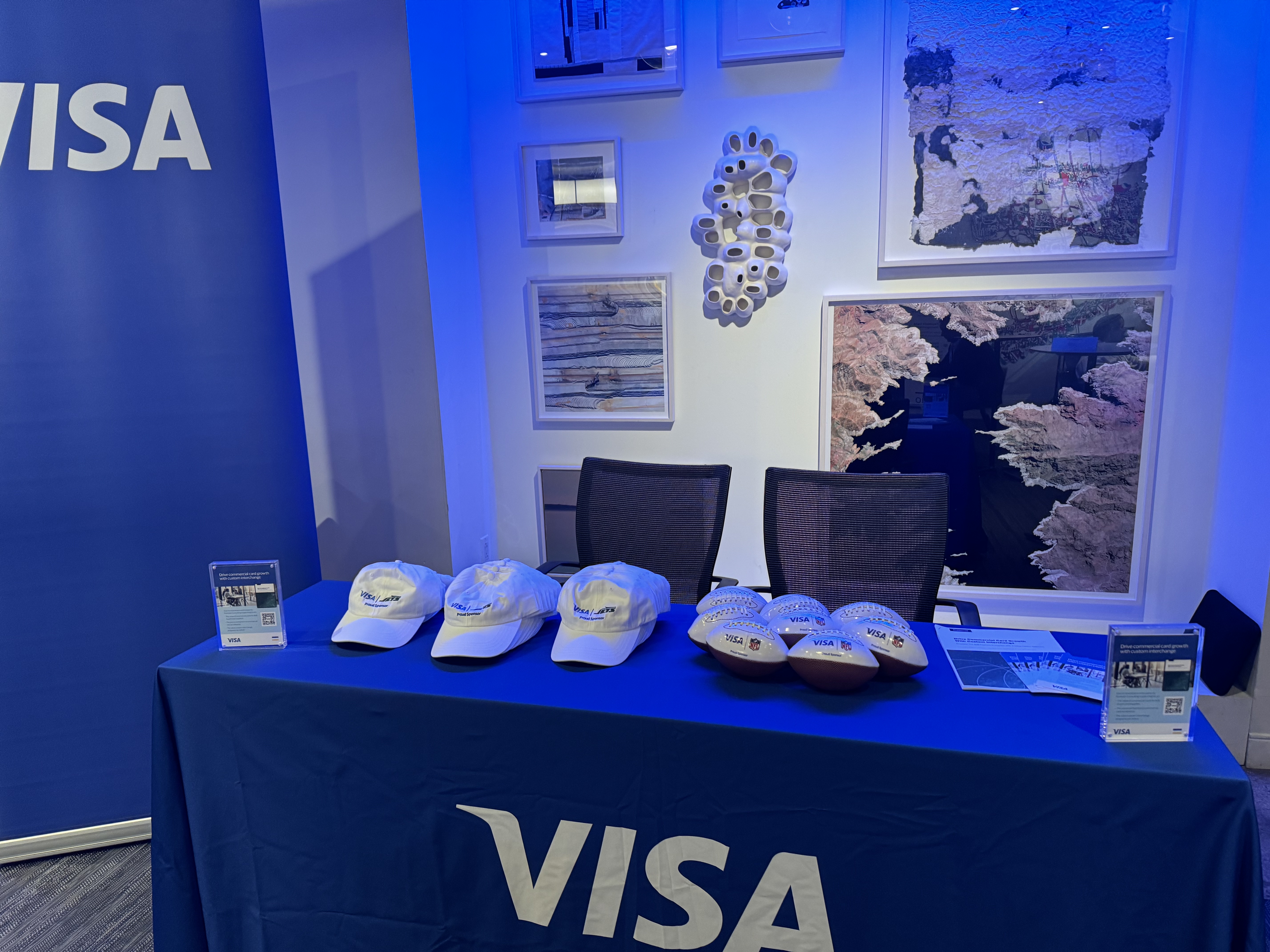 Visa-draped welcome table with co-branded Jets caps and mini footballs
